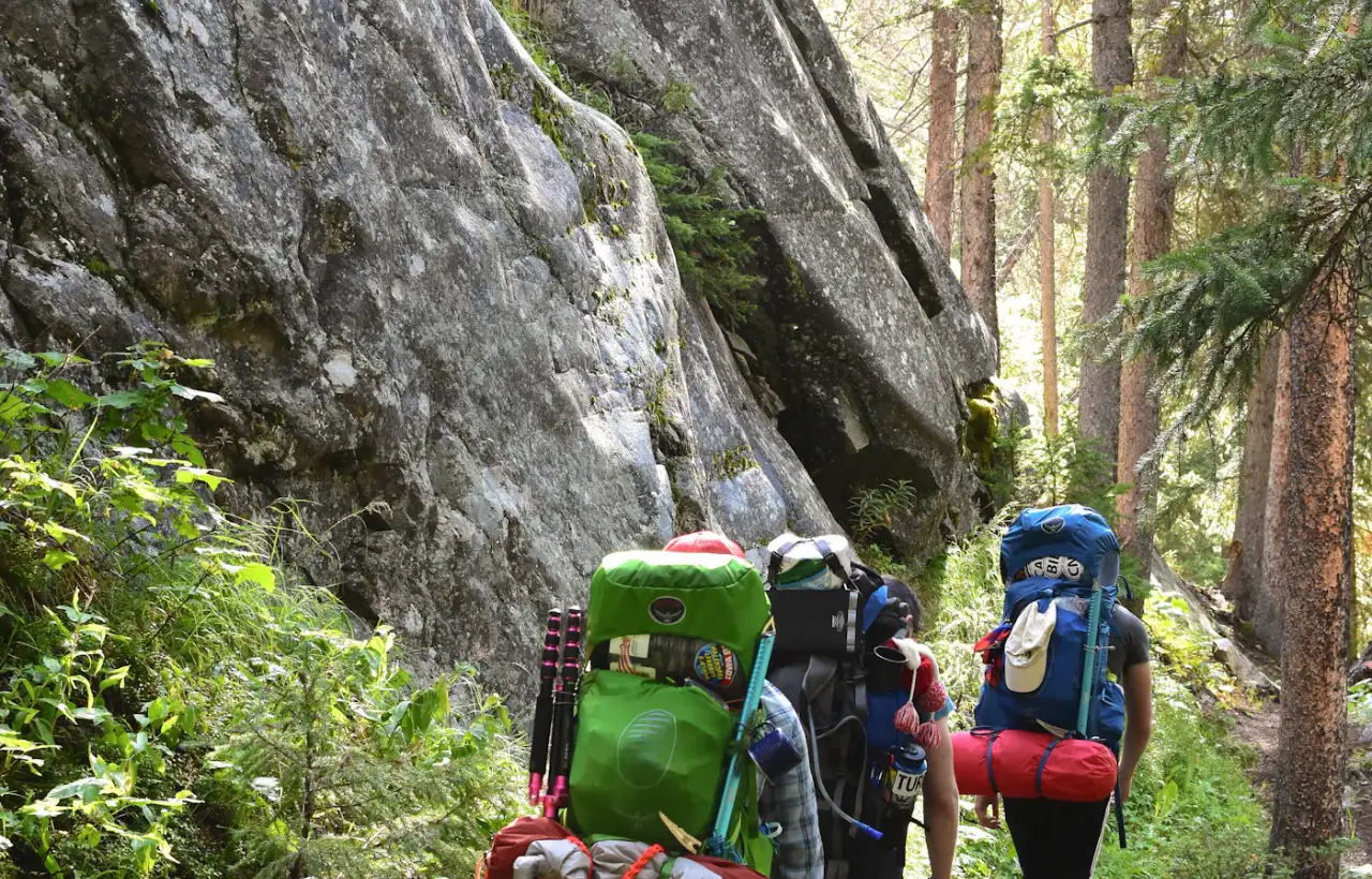 A group of hikers with packs walking together on an outdoor trail