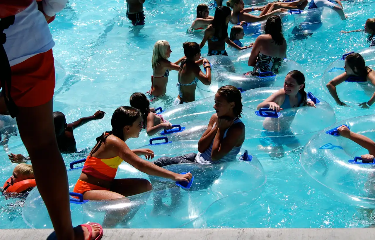 Children swimming and playing in an outdoor swimming pool on a sunny day